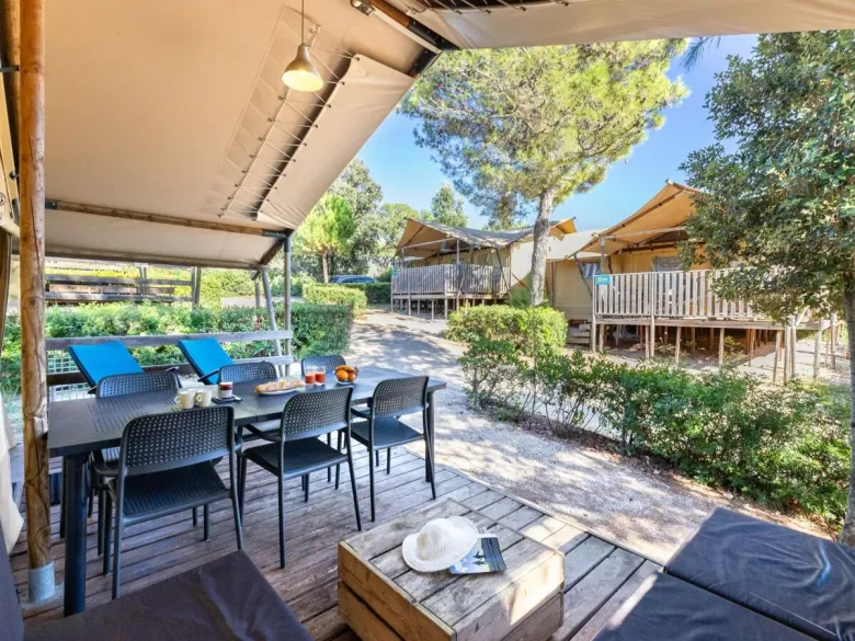 Hotel Roan Lodgetent Premium dysponuje przestronną zadaszoną werandą z częścią wypoczynkową i stołem.