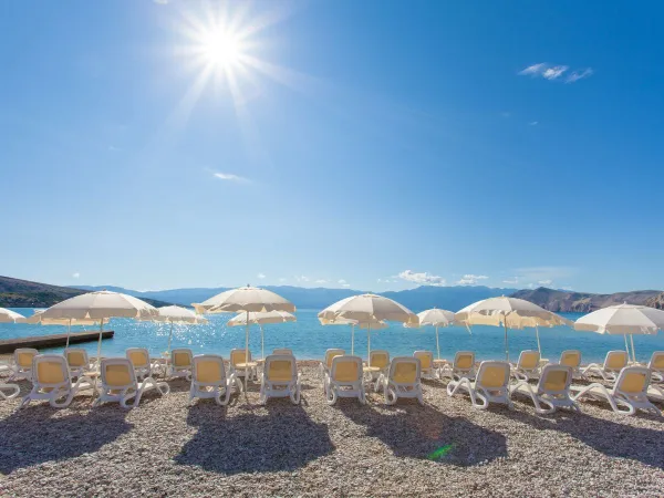 Leżaki na plaży na kempingu Roan Baška Camping Resort.