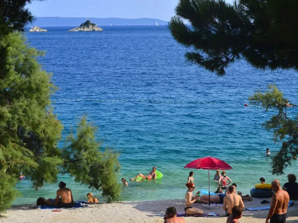 Plaża z błękitnym morzem na kempingu Roan Amadria Park Trogir.