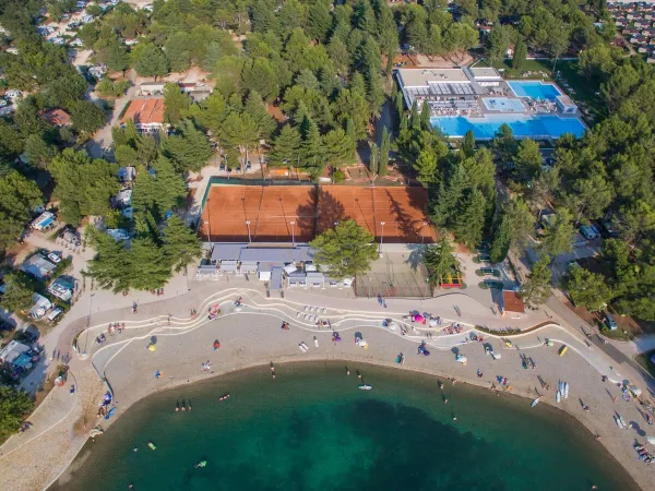 Widok z lotu ptaka na żwirową plażę i bar plażowy na kempingu Roan w Valkanela.