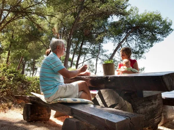 Jedzenie przy stole piknikowym na kempingu Roan Cikat.