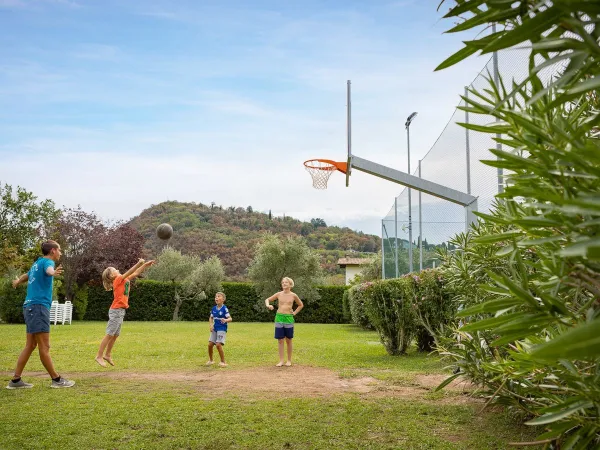 Dzieci grają w koszykówkę na kempingu Roan La Rocca Manerba.