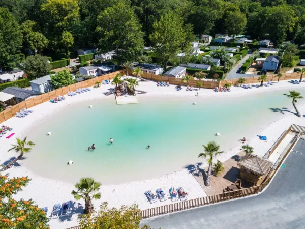 Przegląd basenu lagunowego z piaszczystą plażą na kempingu Roan La Clairière