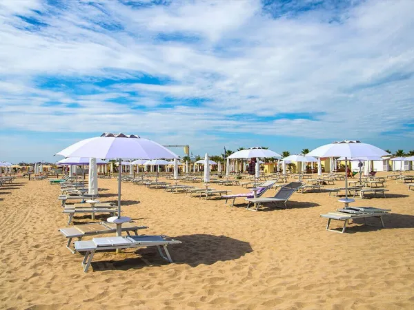 Plaża z leżakami i parasolami na kempingu Roan w Sole Family Camping Village.