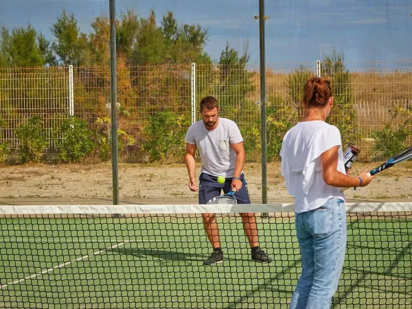 2 osoby grają w tenisa na kempingu Roan Les Dunes.