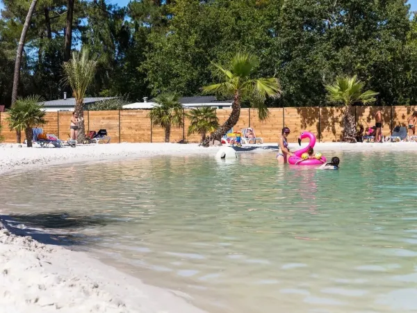 Ludzie opalający się przy basenie lagunowym na kempingu Roan La Clairière.