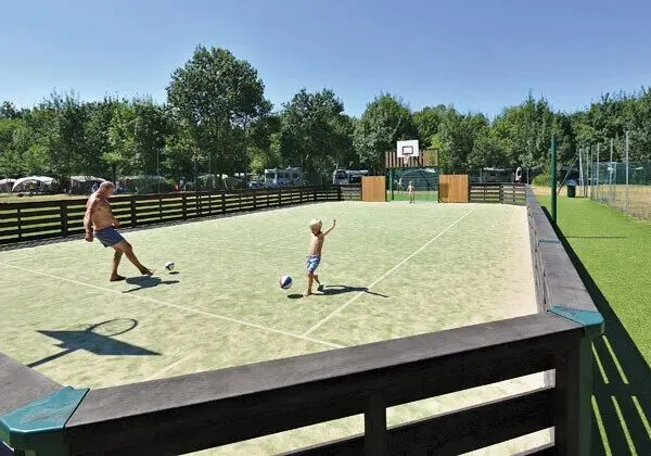 Ojciec i syn grają w piłkę nożną na boisku na kempingu Roan Domaine de La Brèche.