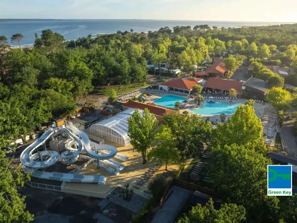 Widok na basen ze zjeżdżalnią i morze w oddali na kempingu Roan Mayotte Vacances.