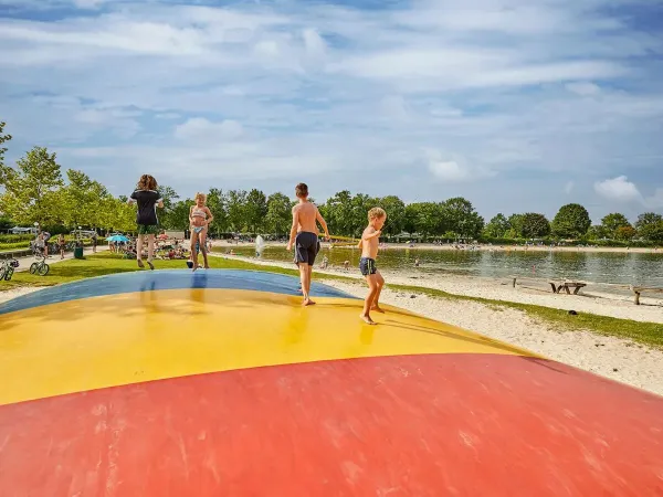Trampolina powietrzna ze skaczącymi dziećmi na plaży na kempingu Roan Terspegelt.