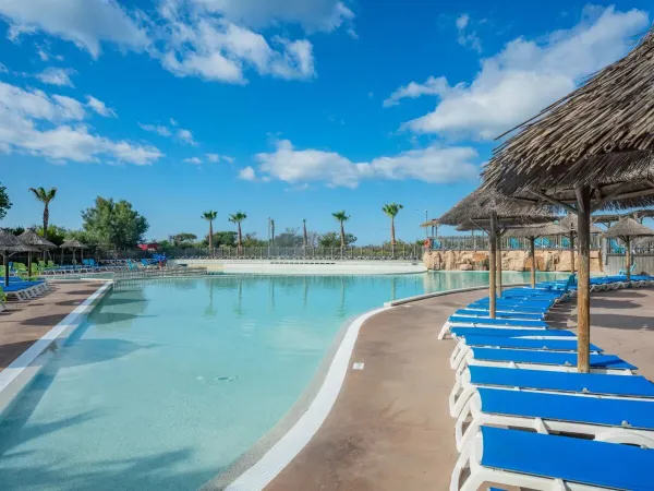 Leżaki i parasole przy basenie na kempingu Roan Les Méditerranées Beach Garden.