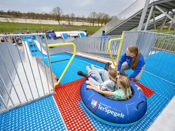 Dzieci zjeżdżają z TubbytJump na kempingu Roan Terspegelt za pomocą opony.