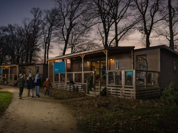 Dzieci przechadzają się zimą obok klimatycznych domków mobilnych na kempingu Roan Marilla Parks Kaatsheuvel.