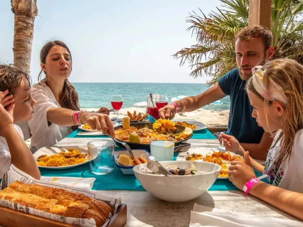 Rodzina spożywa posiłek na plaży na kempingu Roan Alannia Els Prats.