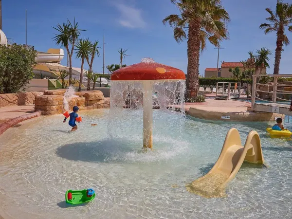 Basen dla dzieci ze zjeżdżalnią i zraszaczem grzybkowym na kempingu Roan Le Petit Mousse.