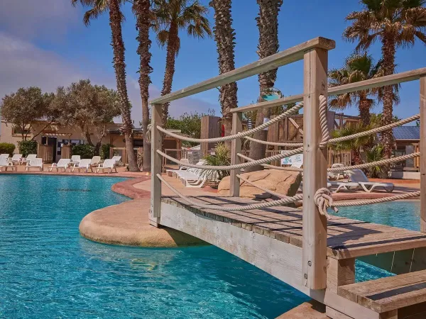 Most i leżaki przy basenie na kempingu Roan Le Petit Mousse.