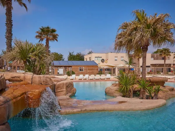 Piękne nasadzenia przy basenie z wodospadem na kempingu Roan Le Petit Mousse.