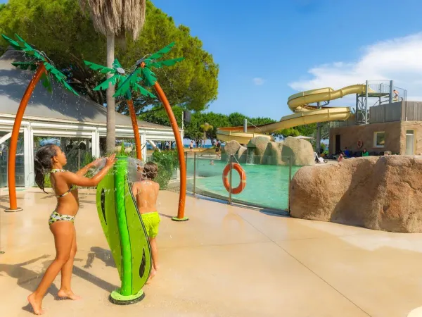 Dzieci bawią się w zraszaczach wodnych na kempingu Roan Arinella Bianca.