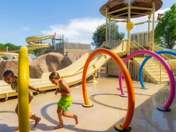 Dzieci biegają przez zraszacze wodne na kempingu Roan Arinella Bianca.