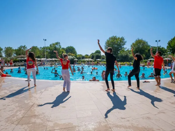 Zespół animatorów entuzjastycznie prowadzi aqua aerobik dla gości.