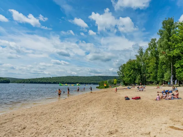 Rodziny opalają się na plaży nad jeziorem na kempingu Roan Le Lac des Vieilles Forges.