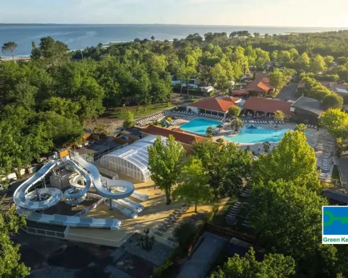 Widok na basen ze zjeżdżalnią i morze w oddali na kempingu Roan Mayotte Vacances.
