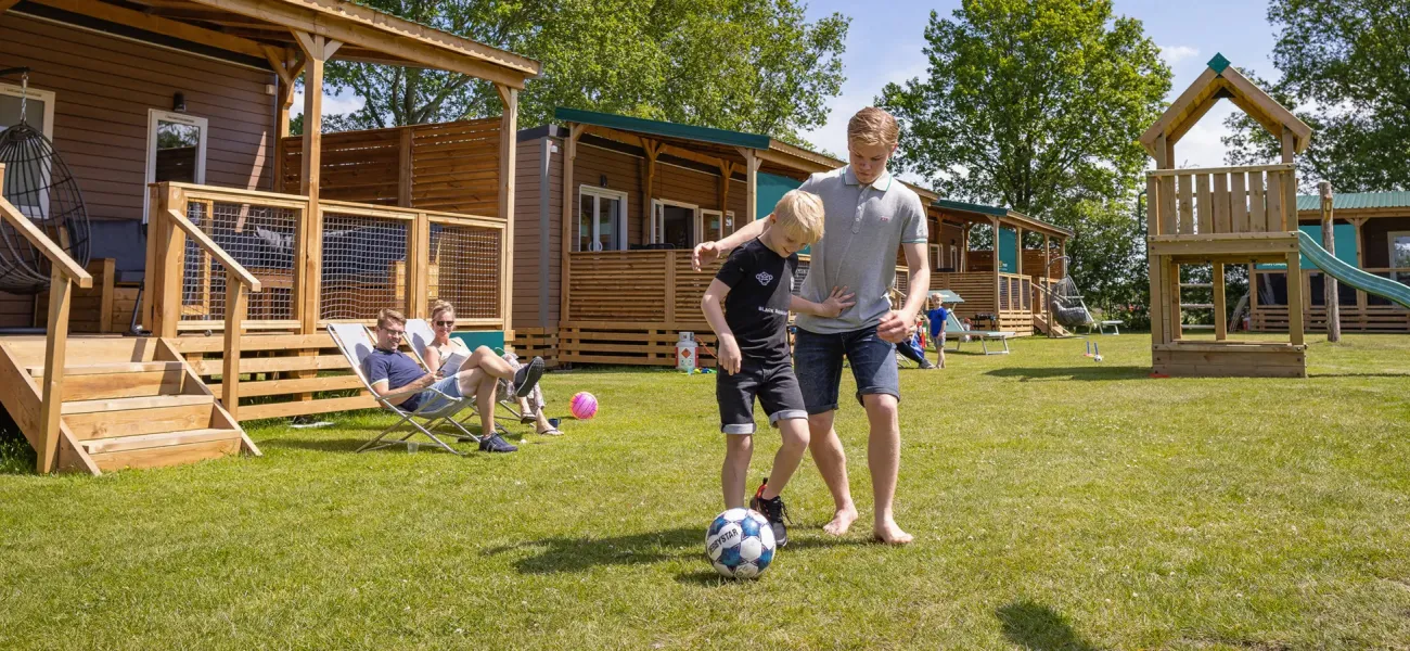 Dzieci grające w piłkę nożną przed zakwaterowaniem Roan na campingu
